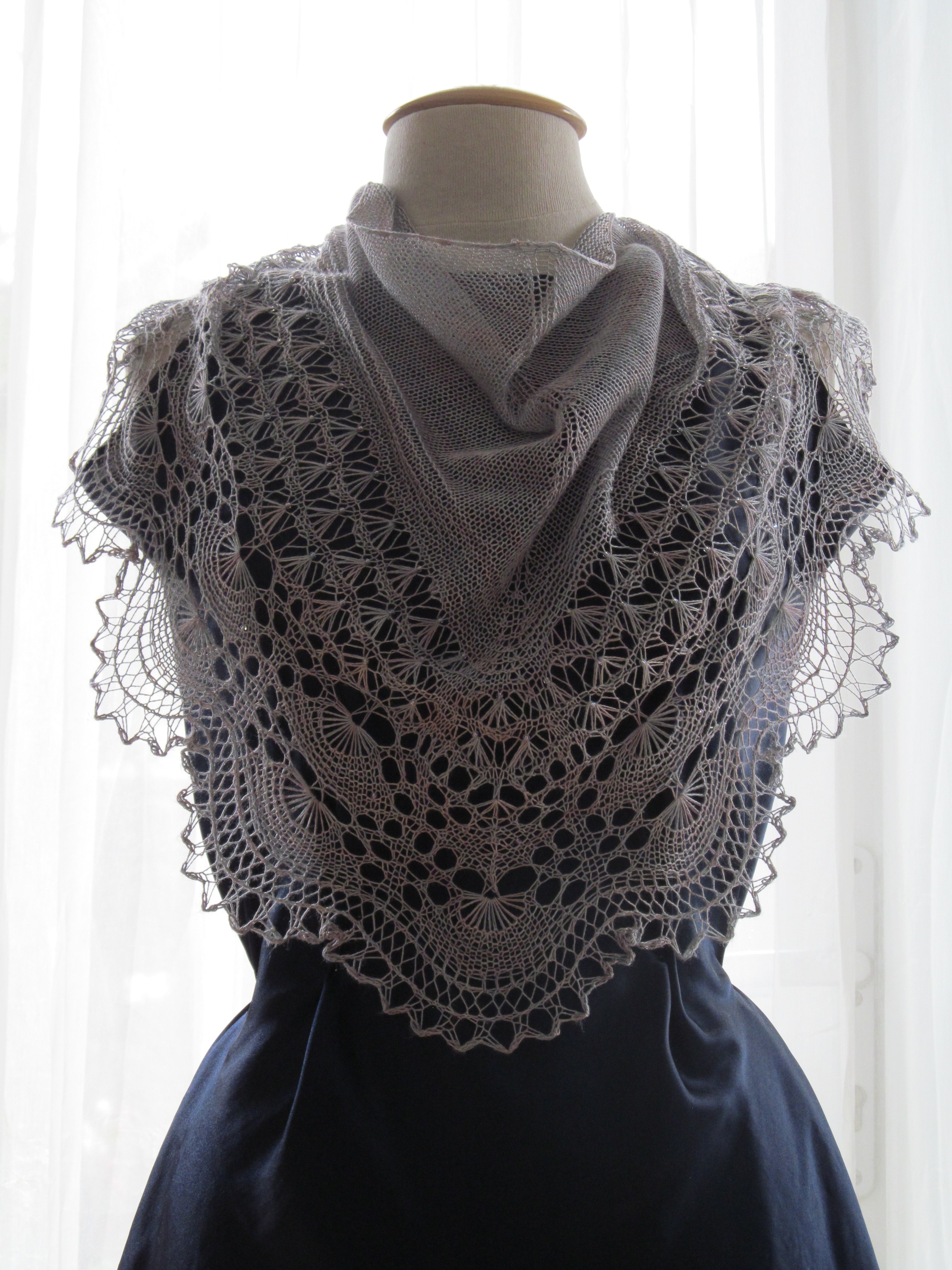 A deep blue mannequin wearing a scalloped shawl in silk